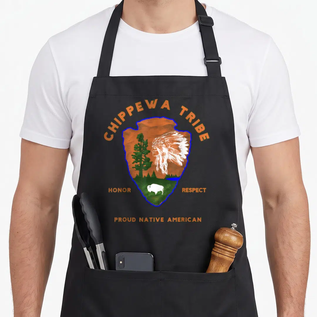 Chippewa tribe native american apron - Arrowhead graphic with chief, bison, tree, and text honoring Chippewa heritage — shown on a black cotton canvas apron against a white background
