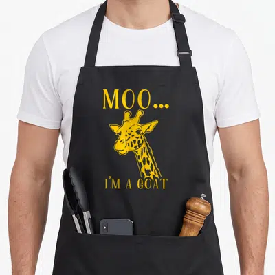 Moo giraffe apron - Yellow giraffe head with text MOO... I'M A GOAT below — shown on a black cotton canvas apron against a white background