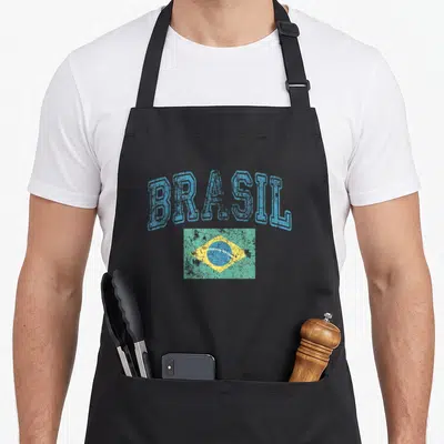Faded pride apron - Arched blue BRASIL text above a distressed rectangular Brazil flag with green background and yellow — shown on a black cotton canvas apron against a white background