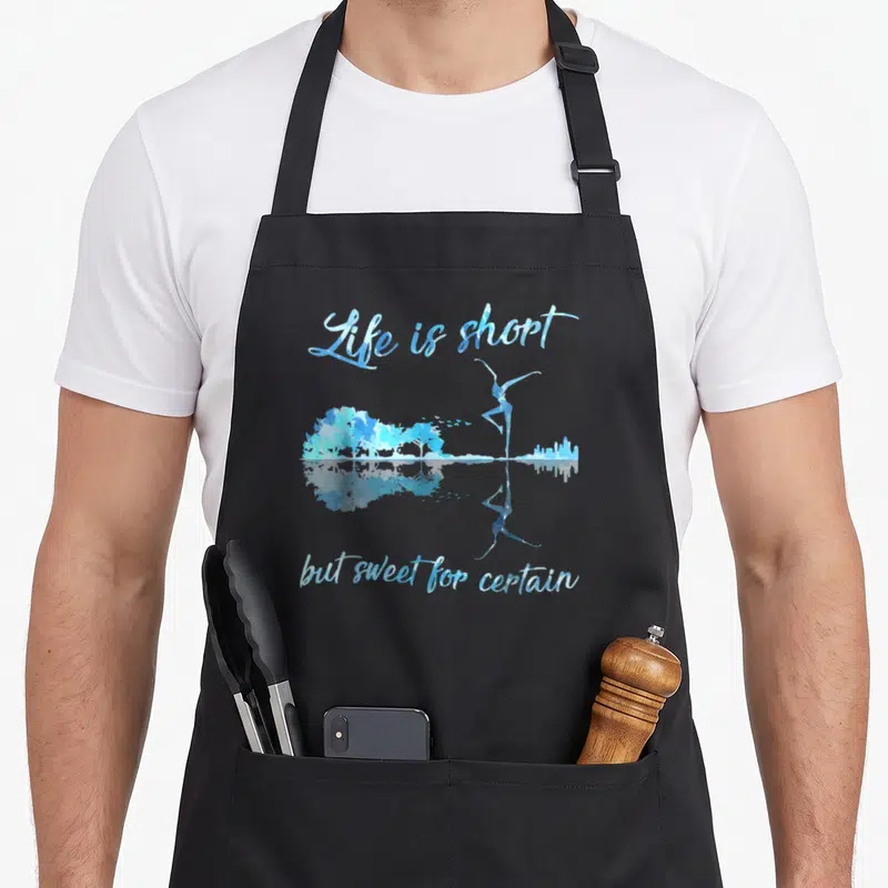 But shortstop apron - Blue watercolor ballerina and trees with Life is short text and mirrored reflection — shown on a black cotton canvas apron against a white background