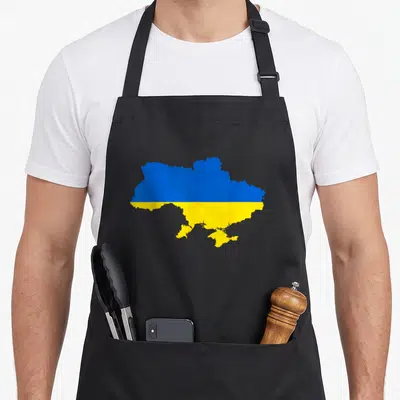 Feel ukrainian aprons - Map of Ukraine silhouette filled with blue top and yellow bottom horizontal bands — shown on a black cotton canvas apron against a white background