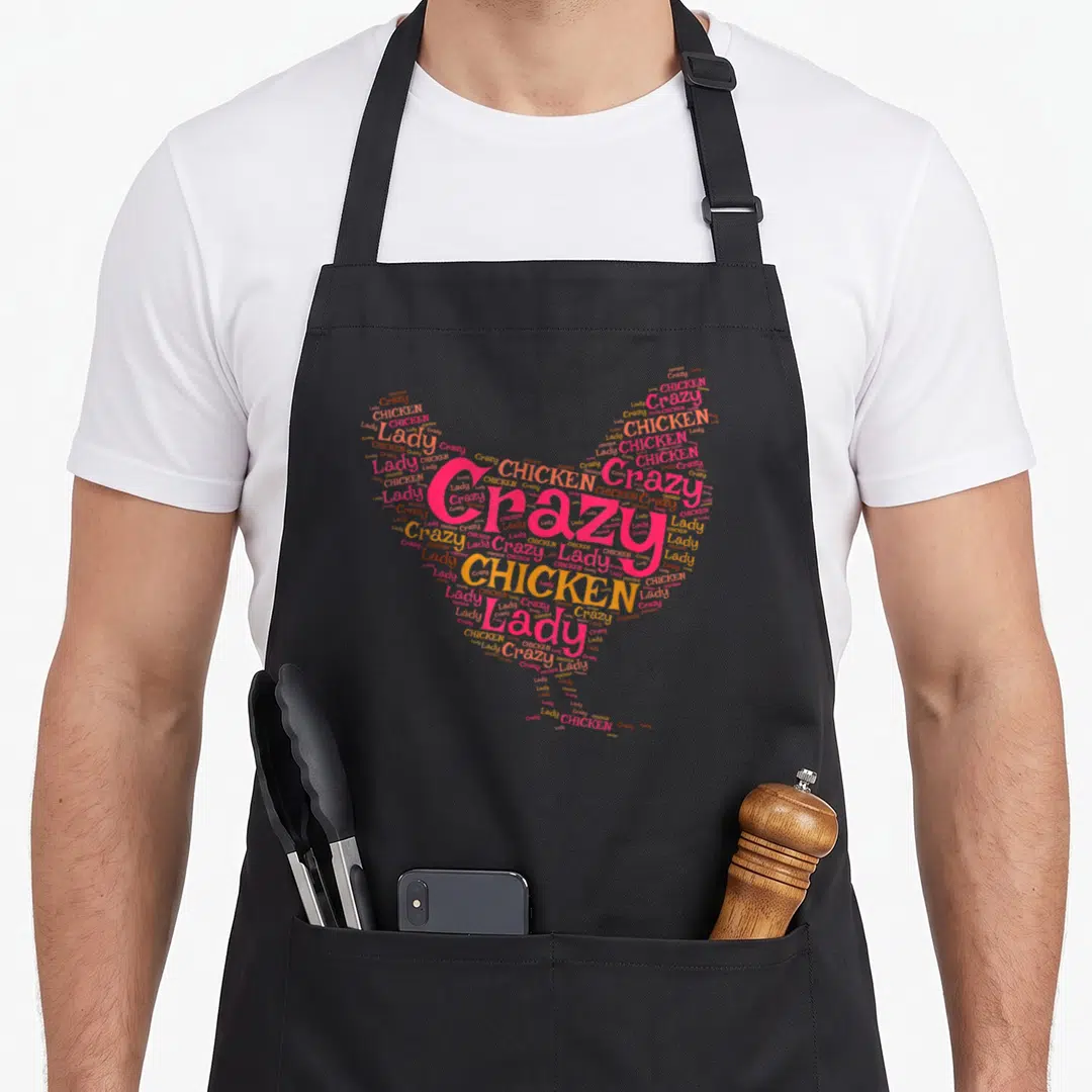 Homesteading chicken with apron - Pink and orange heart shape formed by words Crazy, CHICKEN, Lady in varying sizes — shown on a black cotton canvas apron against a white background