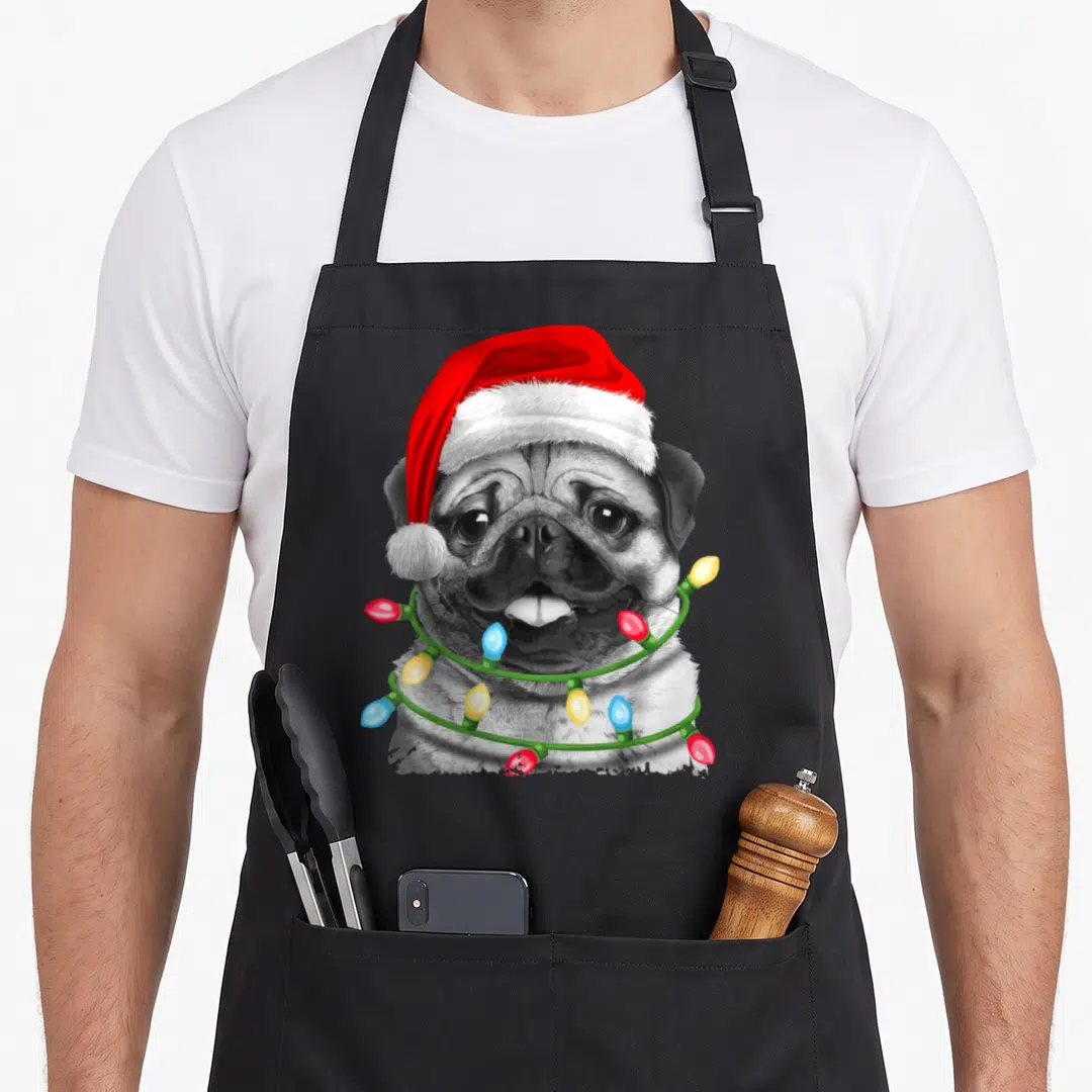 Pugmas christmas tree apron - Realistic pug wearing red Santa hat and wrapped in multicolored Christmas lights — shown on a black cotton canvas apron against a white background