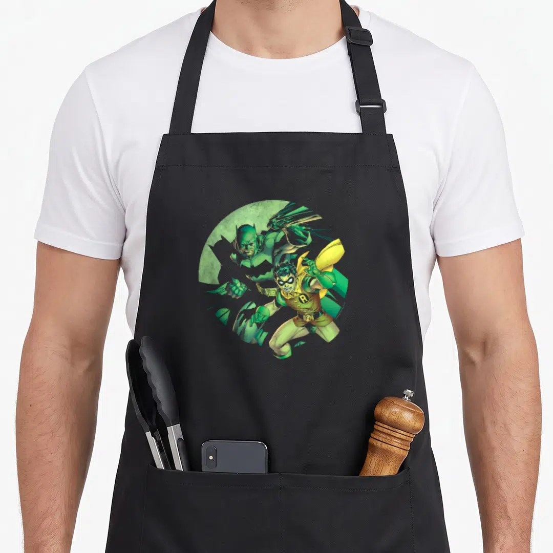 Funny robin animal apron - Cartoon Robin overlapping Batman in green and yellow within a circular background — shown on a black cotton canvas apron against a white background