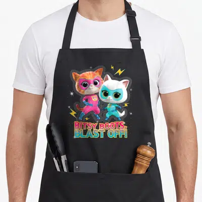 Superkitty junior apron - Two superhero cats with lightning bolts and glittery BITSY BOOTS BLAST OFF text — shown on a black cotton canvas apron against a white background