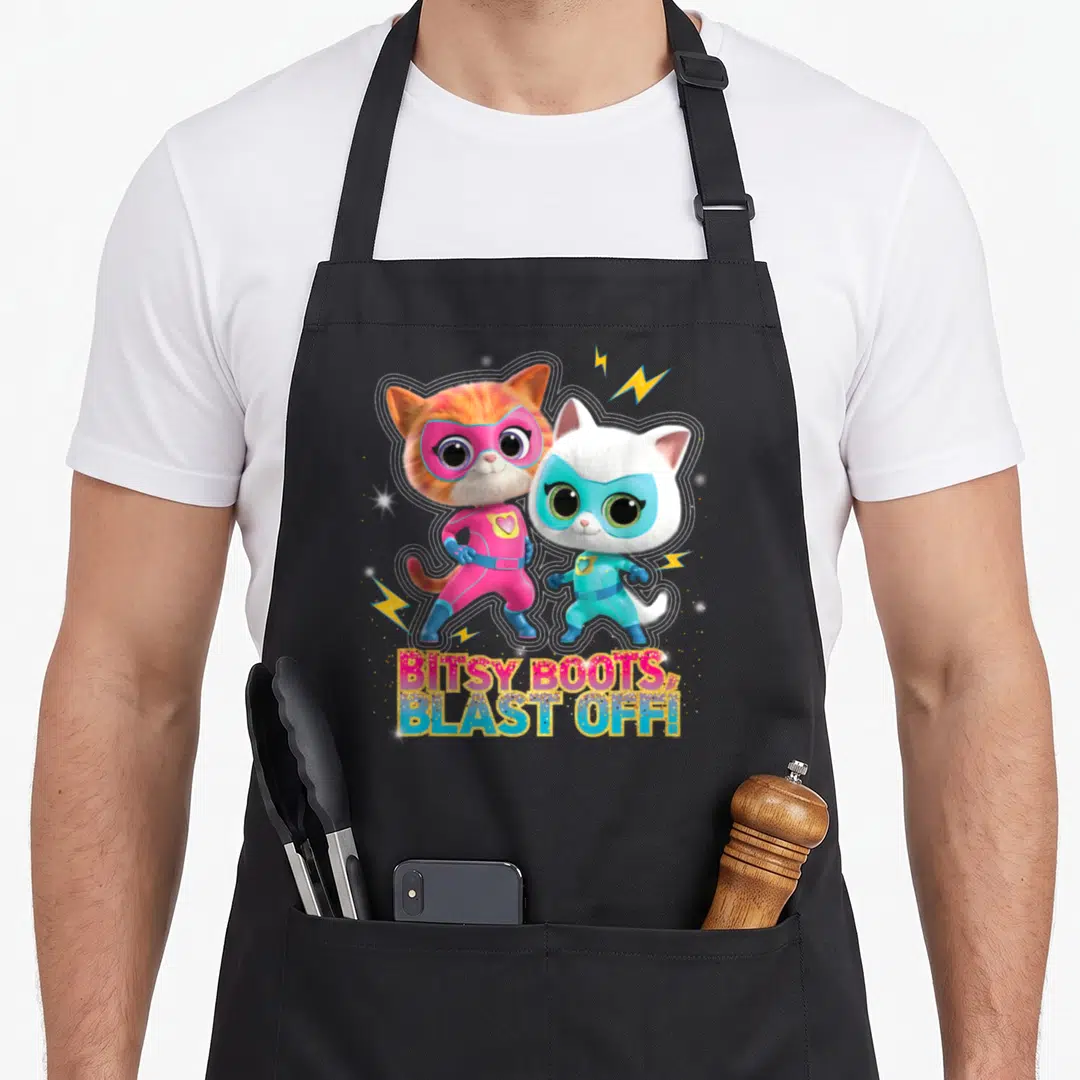 Superkitty junior apron - Two superhero cats with lightning bolts and glittery BITSY BOOTS BLAST OFF text — shown on a black cotton canvas apron against a white background