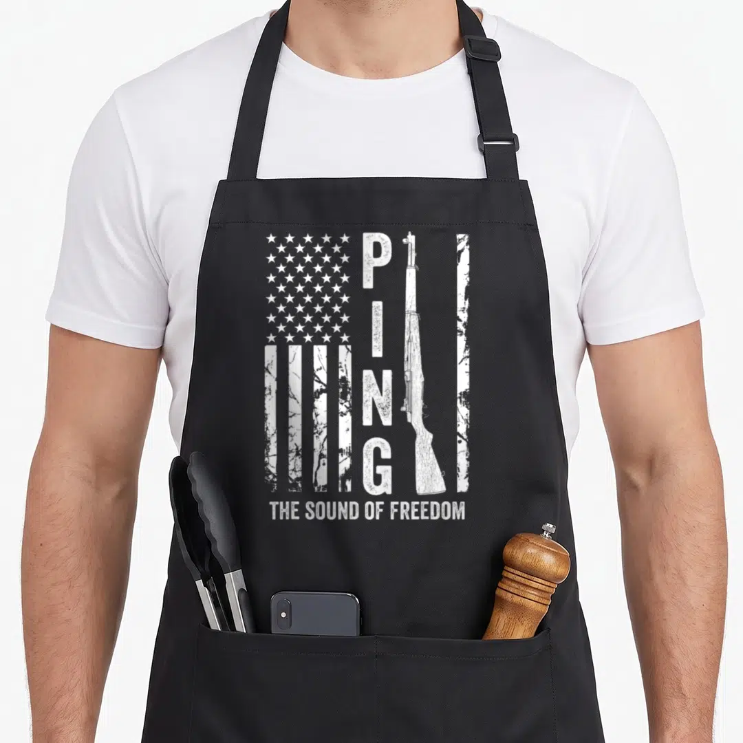 Garand ww2 apron - White distressed US flag with vertical PING text, rifle silhouette, and The Sound of Freedom slogan — shown on a black cotton canvas apron against a white background
