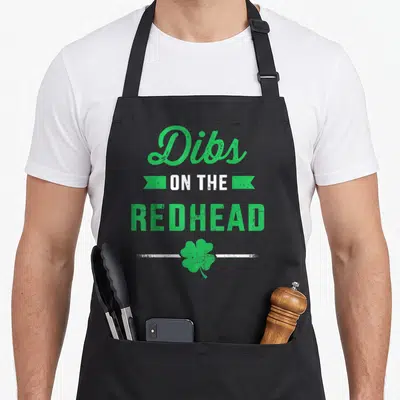 Redhead st patrick day aprons - Green Dibs on the Redhead text with shamrock and white lines — shown on a black cotton canvas apron against a white background