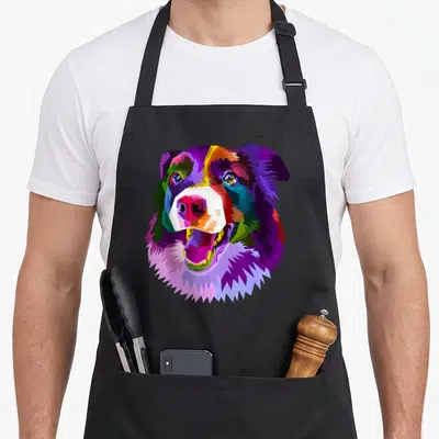Pop border collie apron - Multicolored pixel art dog head in purple blue green red yellow orange — shown on a black cotton canvas apron against a white background