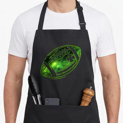 Football irish st patrick day aprons - Glowing green realistic American football with integrated shamrock on black — shown on a black cotton canvas apron against a white background
