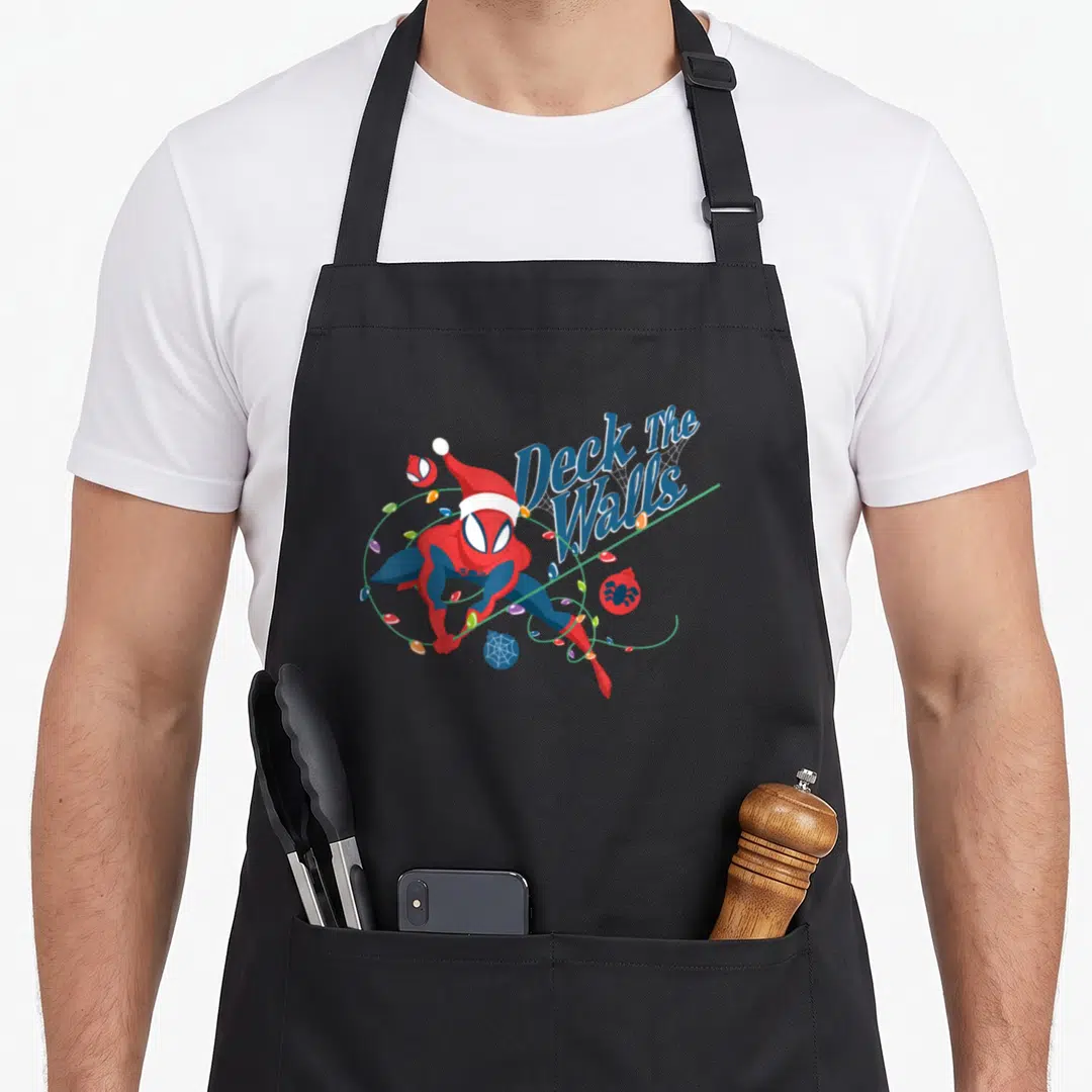 Deck holiday apron - Spider-Man in Santa hat holding Christmas lights next to Deck The Walls script — shown on a black cotton canvas apron against a white background