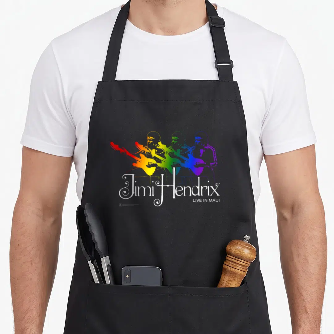 Jimi rainbow apron - Three rainbow gradient silhouettes of Jimi Hendrix playing guitar with white text below — shown on a black cotton canvas apron against a white background