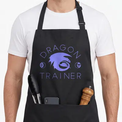 Trainer dragon apron - Purple dragon silhouette with DRAGON TRAINER text and lightning bolt skull icons — shown on a black cotton canvas apron against a white background