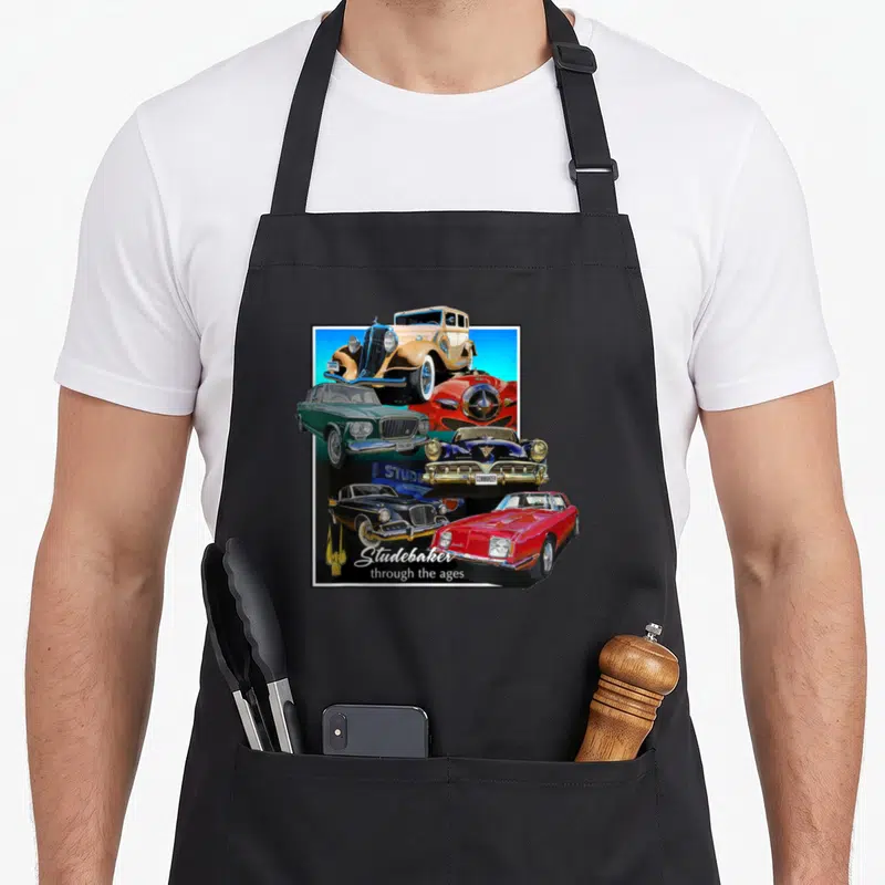 Studebaker auto apron - Five vintage Studebaker cars in red, blue, tan, green, and black with white border — shown on a black cotton canvas apron against a white background