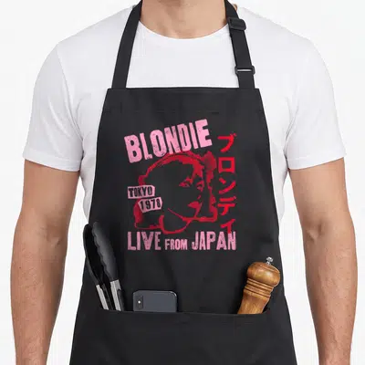 Blondie japan apron - Distressed pink Blondie portrait with Tokyo 1978 text and vertical Japanese characters — shown on a black cotton canvas apron against a white background