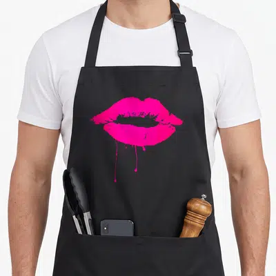 Lip hot pink apron - Pair of pink lips with paint drips, minimalist graphic, no text — shown on a black cotton canvas apron against a white background