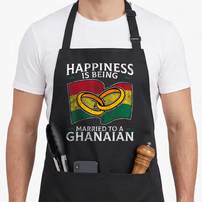 Ghanaian heritage aprons - Distressed text around waving flag with two interlocking rings in red yellow green white — shown on a black cotton canvas apron against a white background