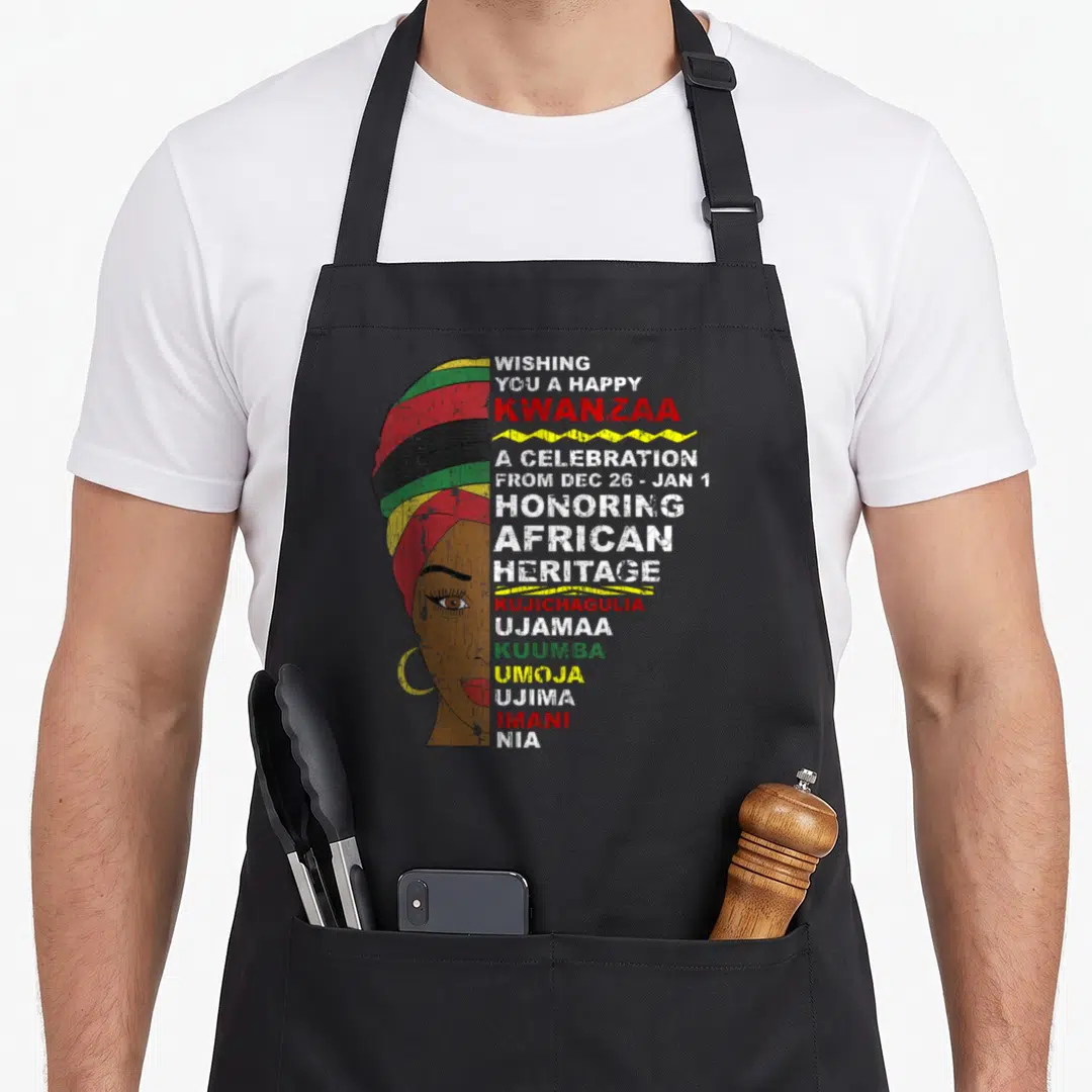 Kwanzaa african apron - Woman in striped turban with Kwanzaa greeting and seven principles text in red green yellow — shown on a black cotton canvas apron against a white background