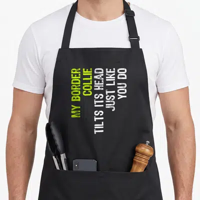 Tilt border collie apron - Vertical lime green and white text reading My Border Collie Tilts Its Head Just Like You Do — shown on a black cotton canvas apron against a white background