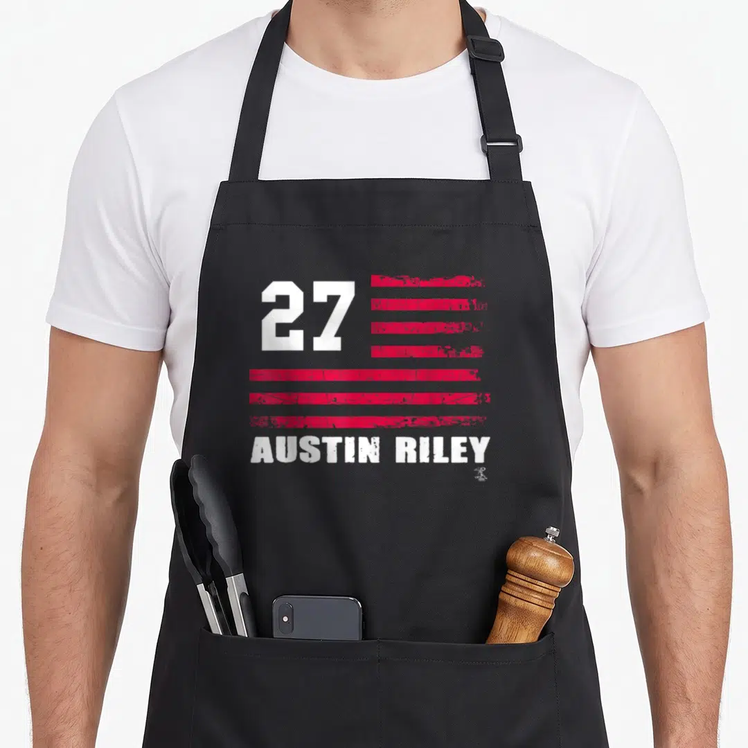 Riley austin texas apron - 27 next to distressed red and white striped flag with AUSTIN RILEY text below — shown on a black cotton canvas apron against a white background