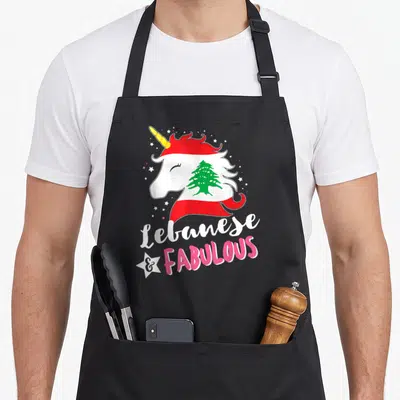 Lebanese unicorn apron - Cartoon unicorn head with Lebanese flag and text Lebanese & Fabulous — shown on a black cotton canvas apron against a white background