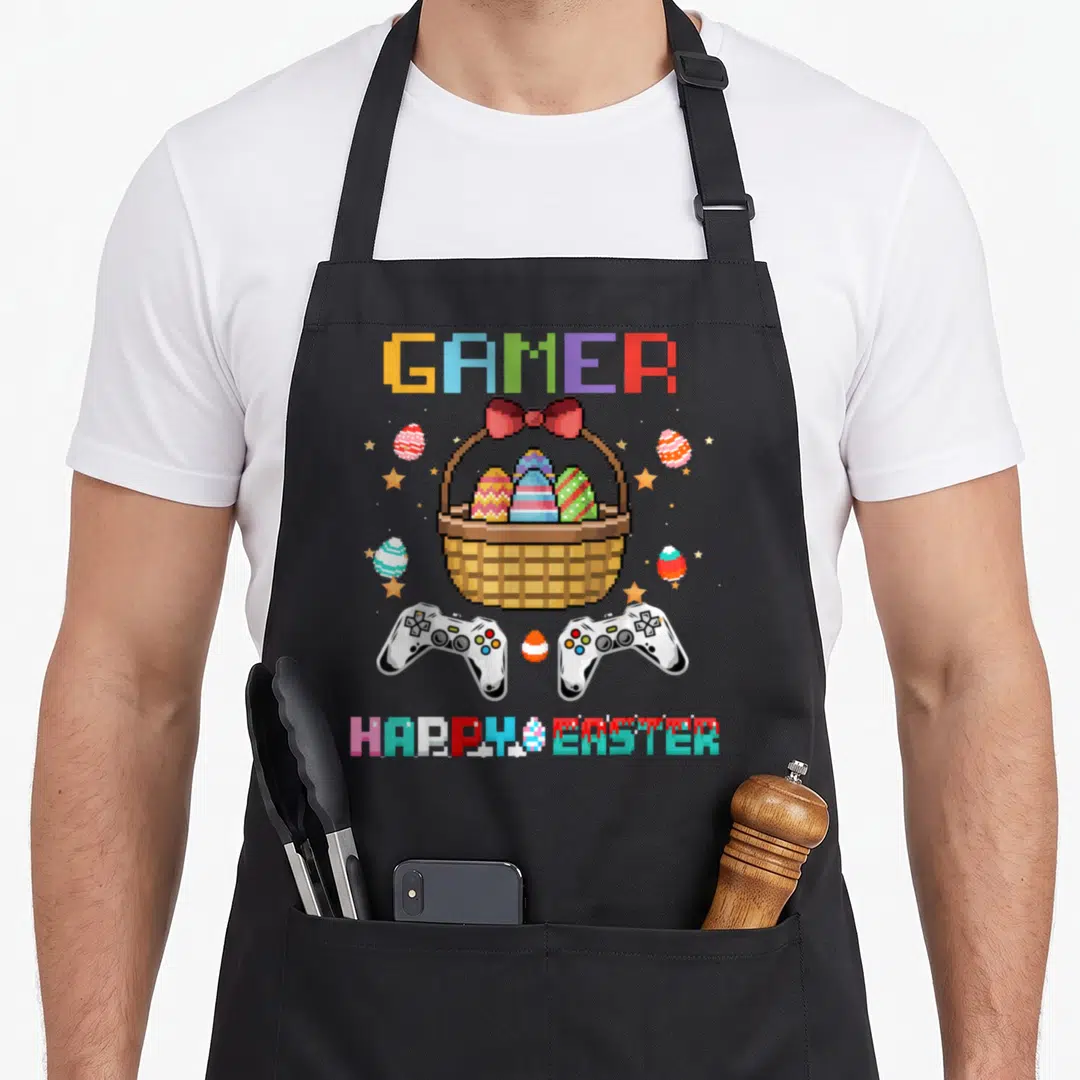 Video basket apron - Pixel art GAMER and HAPPY EASTER with brown basket, eggs, and two white controllers — shown on a black cotton canvas apron against a white background