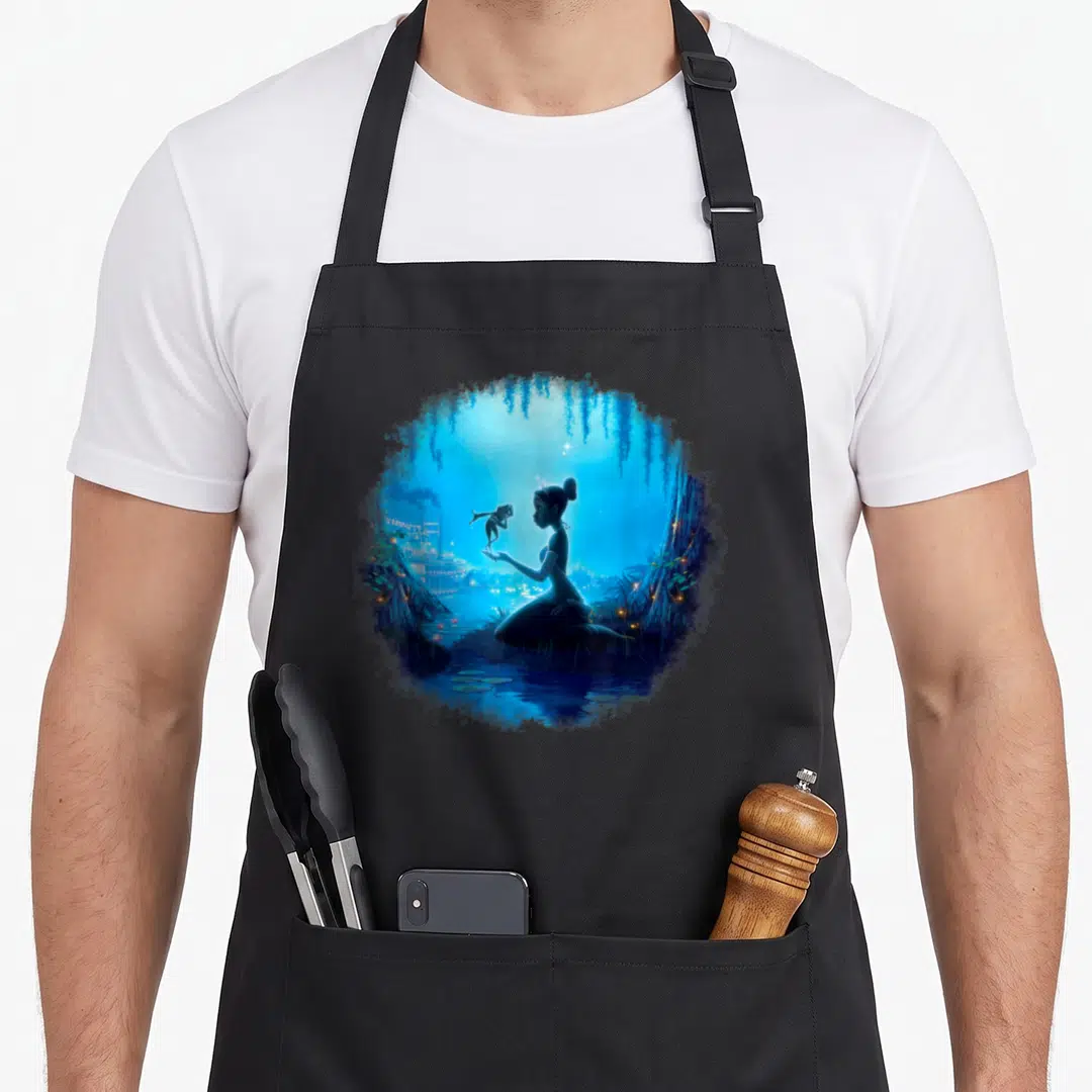 Swamp princess apron - Circular watercolor of woman silhouette holding frog in blue night swamp with willow branches — shown on a black cotton canvas apron against a white background