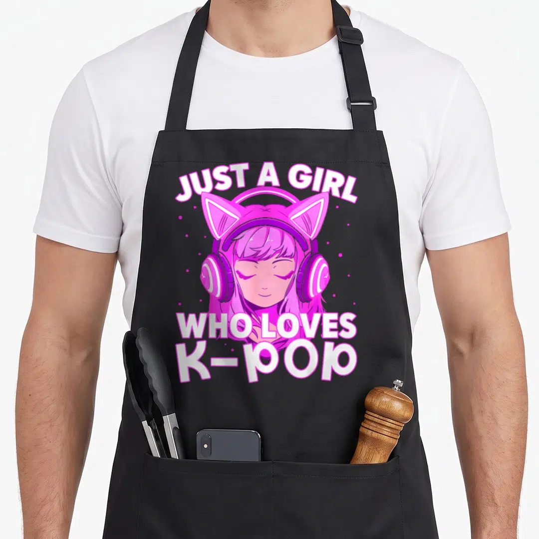 Listening korean apron - Pink cartoon girl with cat-ear headphones and text JUST A GIRL WHO LOVES K-POP — shown on a black cotton canvas apron against a white background