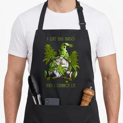 Bud gnome apron - Cartoon gnome holding cannabis buds with arched text I LIKE BIG BUDS AND I CANNOT LIE — shown on a black cotton canvas apron against a white background