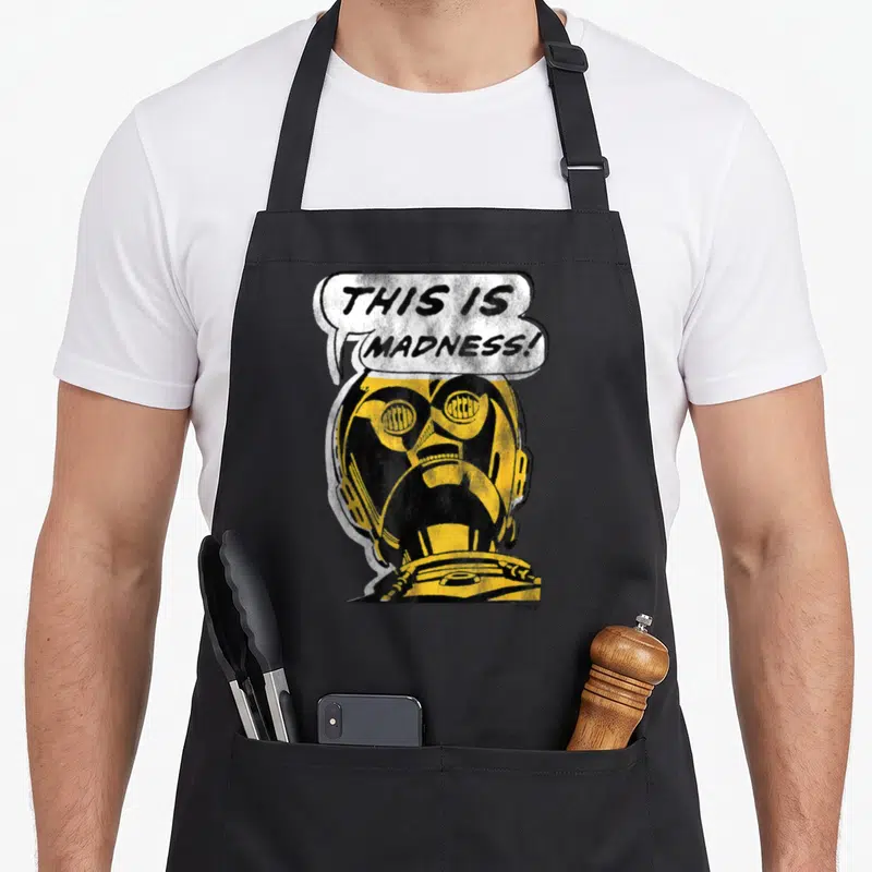 3po c apron - Distressed yellow helmet with THIS IS MADNESS speech bubble in black and white — shown on a black cotton canvas apron against a white background