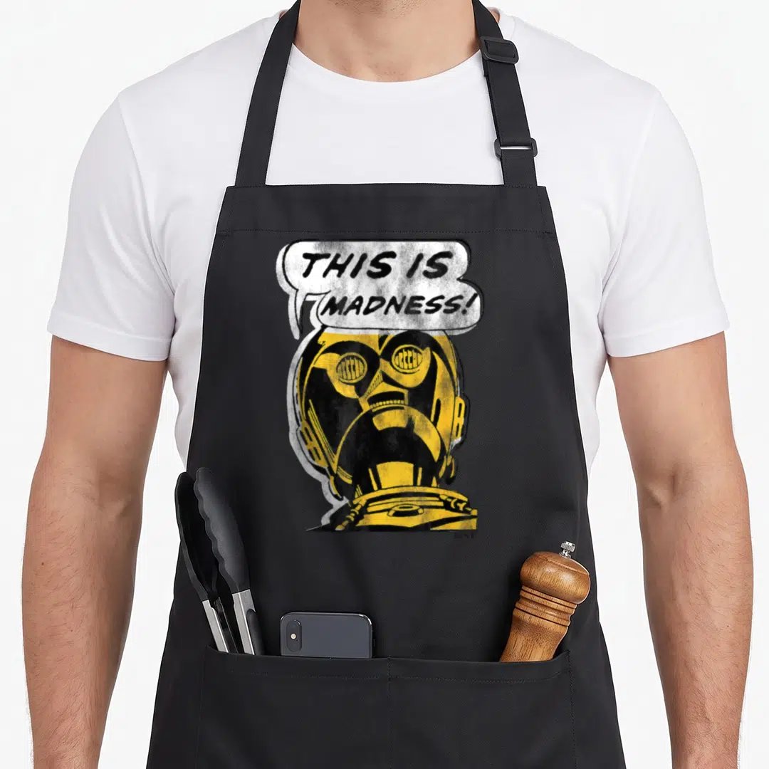 3po c apron - Distressed yellow helmet with THIS IS MADNESS speech bubble in black and white — shown on a black cotton canvas apron against a white background
