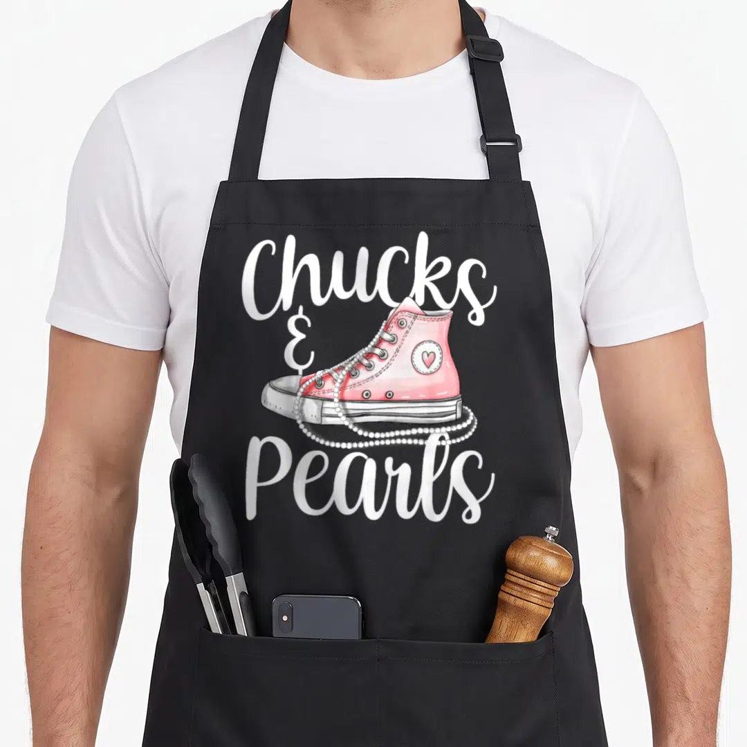 Pearl us aprons - Pink sneaker with draped pearl necklace and text Chucks & Pearls — shown on a black cotton canvas apron against a white background