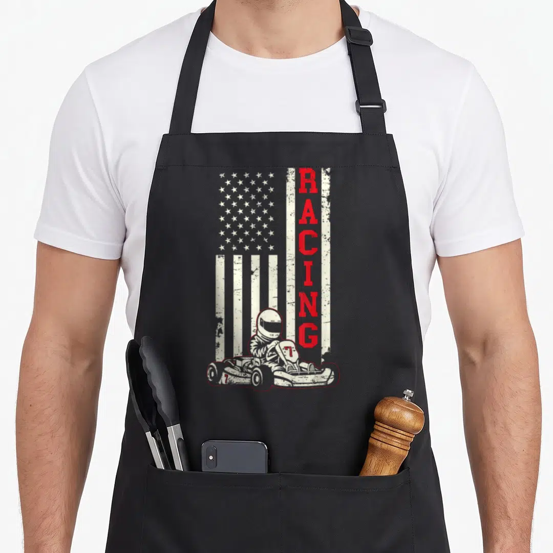 Karting american flag apron - Distressed USA flag with vertical red RACING text and go-kart driver illustration — shown on a black cotton canvas apron against a white background