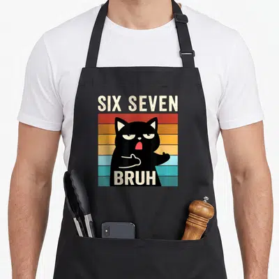 Seven cat apron - Black cat over multi-colored stripes with six seven bruh text in retro style — shown on a black cotton canvas apron against a white background