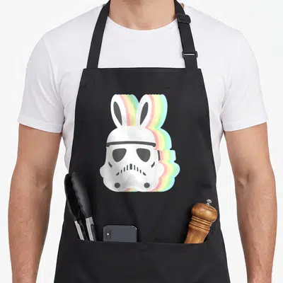 Easter bunny apron - White stormtrooper helmet with bunny ears and colorful offset silhouettes in pink yellow green — shown on a black cotton canvas apron against a white background