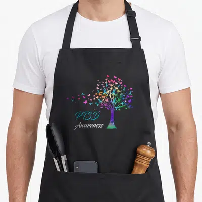 Ptsd tree apron - Watercolor tree with ribbons and butterflies in purple, cyan, pink, and blue — shown on a black cotton canvas apron against a white background