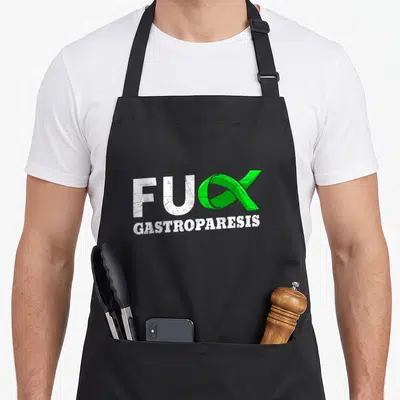 Paralysis ribbon apron - Green ribbon replacing X in white FUX GASTROPARESIS distressed text — shown on a black cotton canvas apron against a white background