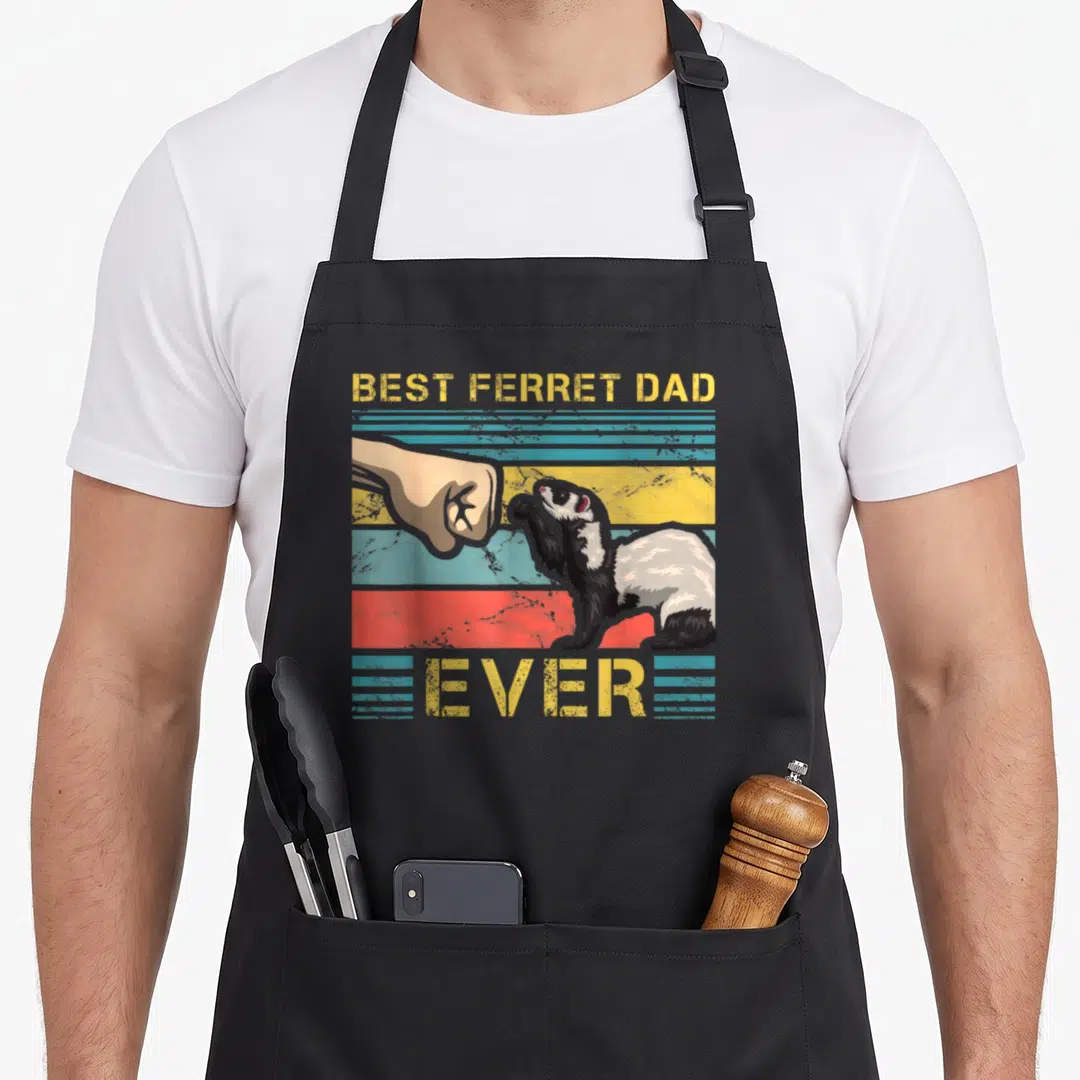 Ferret father day apron - BEST FERRET DAD EVER text above and below ferret hand fist bump on yellow blue red black — shown on a black cotton canvas apron against a white background