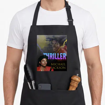 Cute thriller michaels apron - Two Michael Jackson photos over stormy sky with purple THRILLER and yellow name text — shown on a black cotton canvas apron against a white background
