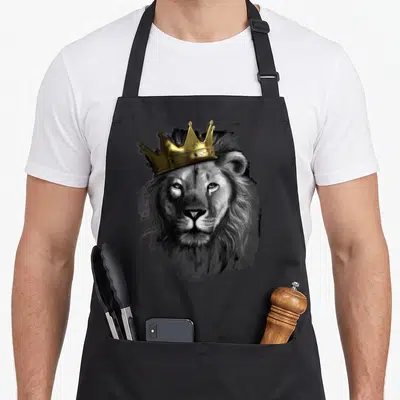 Crown king apron - Realistic grey lion head wearing a gold crown with blue gems — shown on a black cotton canvas apron against a white background