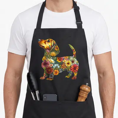 Dachshund floral apron - Cartoon dachshund silhouette filled with orange, yellow, red, and green flowers — shown on a black cotton canvas apron against a white background