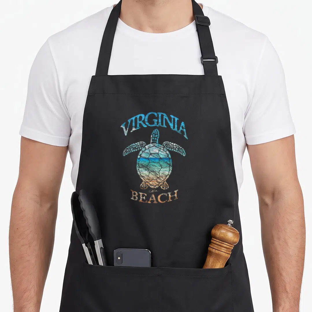 Jcomb virginia beach apron - Distressed sea turtle with Virginia Beach text and landscape filled shell in blue orange — shown on a black cotton canvas apron against a white background