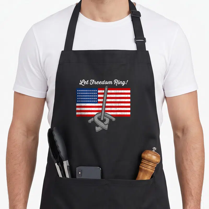 Freedom throwing apron - Distressed USA flag with grey horseshoe stake and Let Freedom Ring text — shown on a black cotton canvas apron against a white background