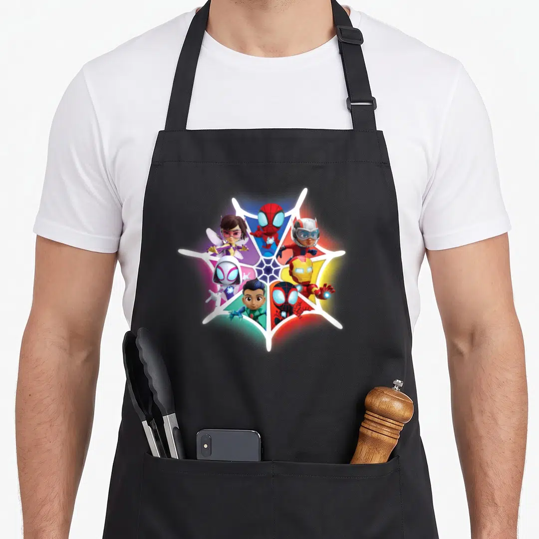 Spidey friends apron - Six superheroes in cartoon style inside a white spider web with red blue white and yellow accents — shown on a black cotton canvas apron against a white background
