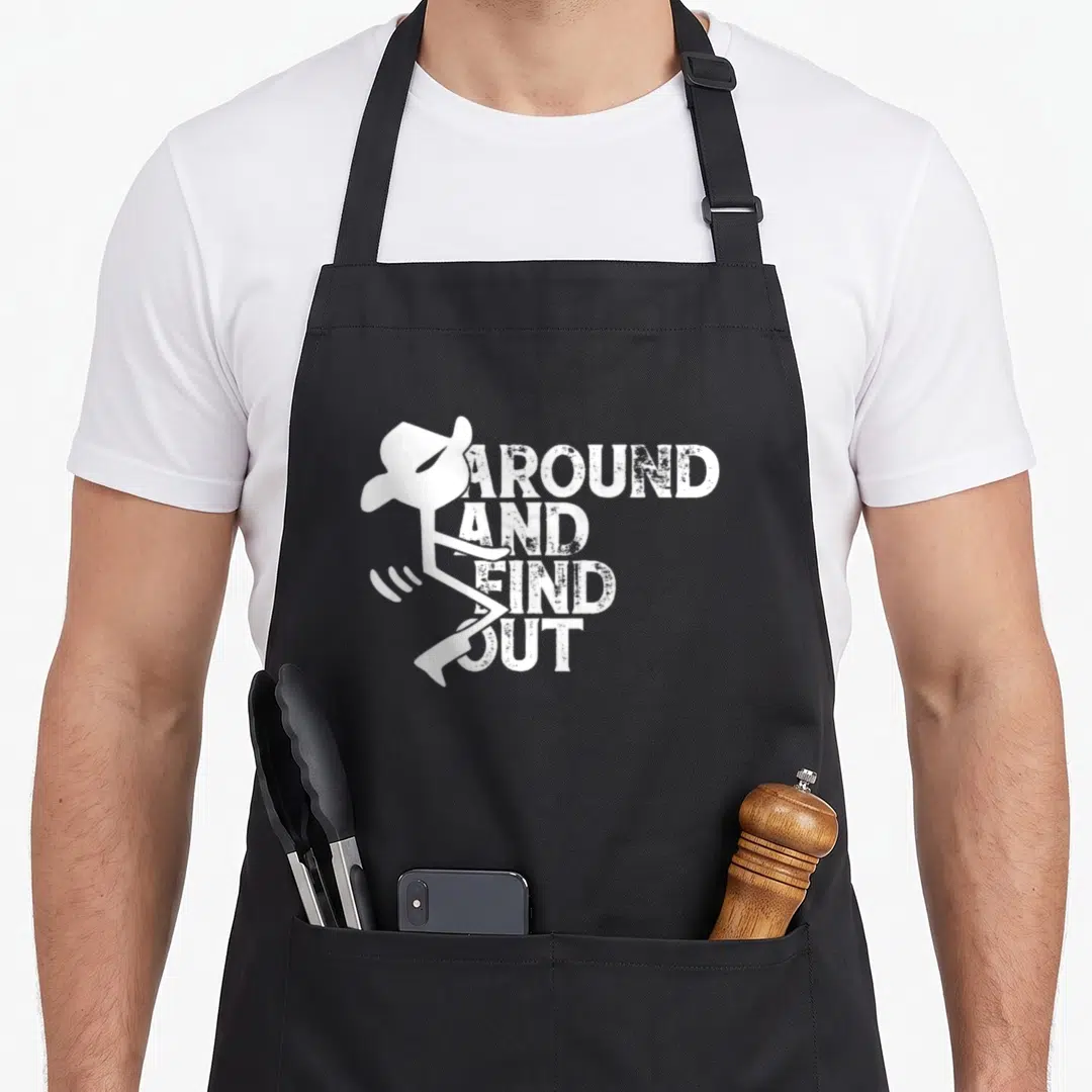 Cute around find aprons for grilling - White stick figure cowboy hat beside four stacked distressed words AROUND — shown on a black cotton canvas apron against a white background