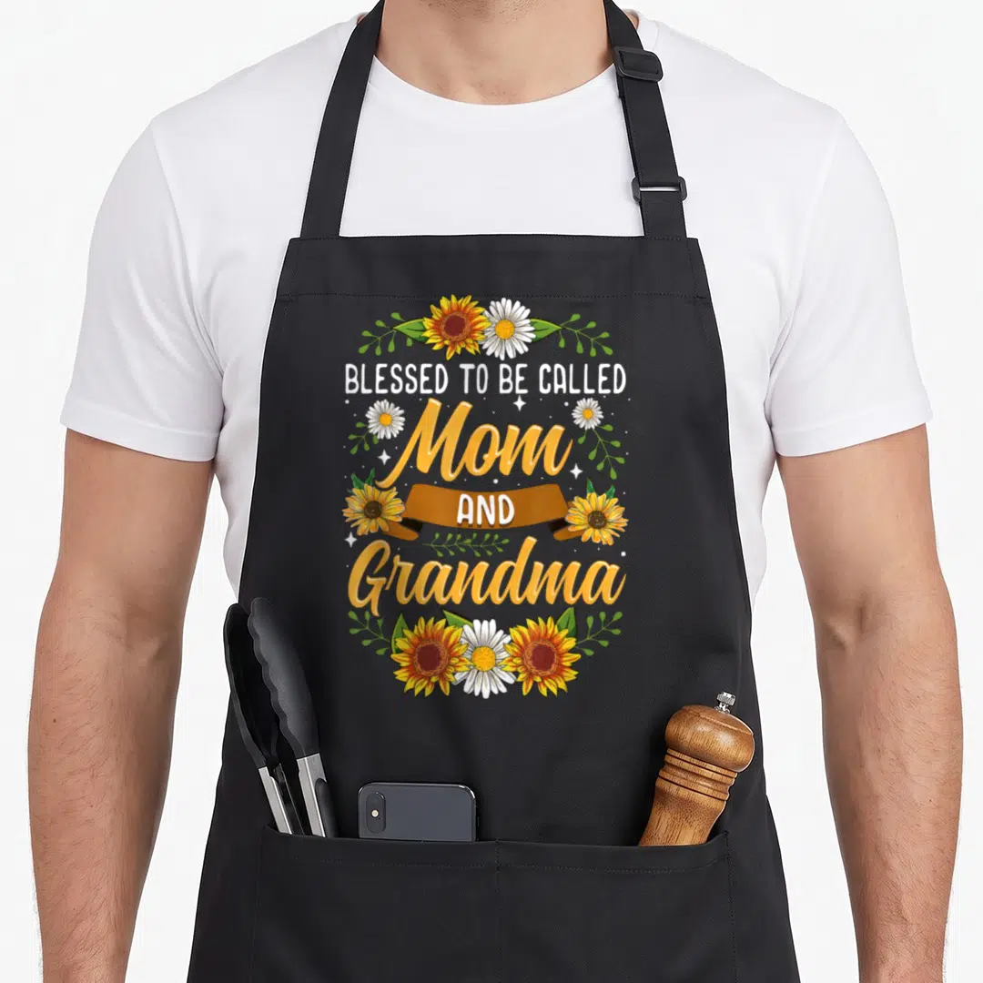 Sunflower grandma apron - Blessed to be called Mom and Grandma text with sunflowers and daisies in yellow white green — shown on a black cotton canvas apron against a white background