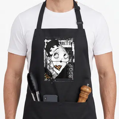 Stamp punk rock apron - Distressed Betty Boop portrait with BETTY BOOP text and leopard heart in black white orange — shown on a black cotton canvas apron against a white background