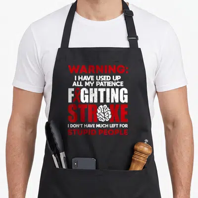 Vintage survivor stroke awareness apron - Red ribbon and white brain inside stacked red and white distressed warning — shown on a black cotton canvas apron against a white background