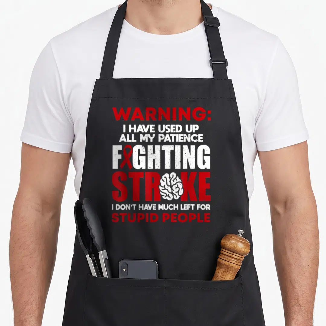Vintage survivor stroke awareness apron - Red ribbon and white brain inside stacked red and white distressed warning — shown on a black cotton canvas apron against a white background