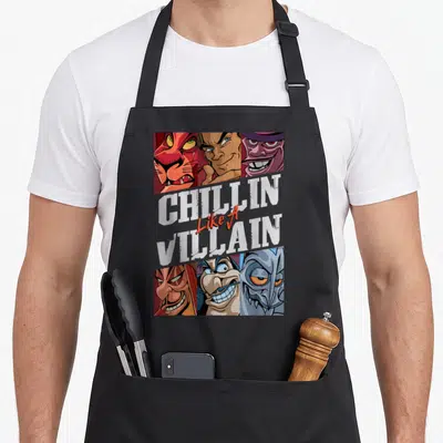 Chillin novelty apron - Six cartoon villain faces surrounding stacked white and red text reading CHILLIN Like A VILLAIN — shown on a black cotton canvas apron against a white background